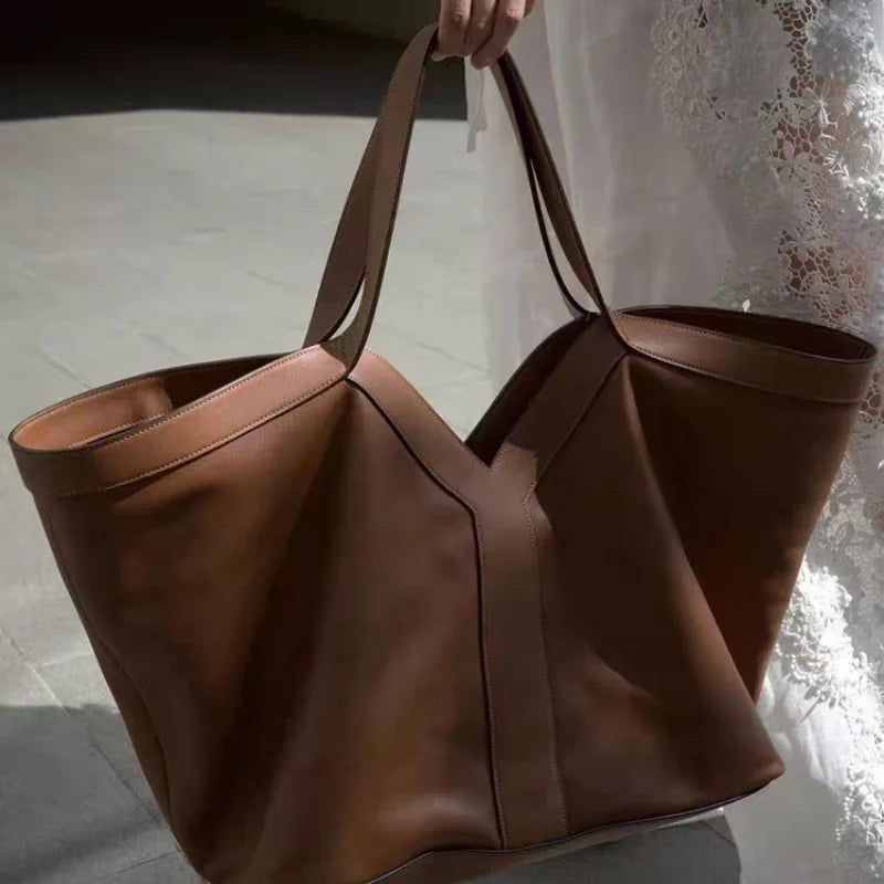 Large black V-cut leather tote bag with double shoulder straps on display