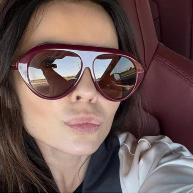 Person wearing large sunglasses sitting in a car.