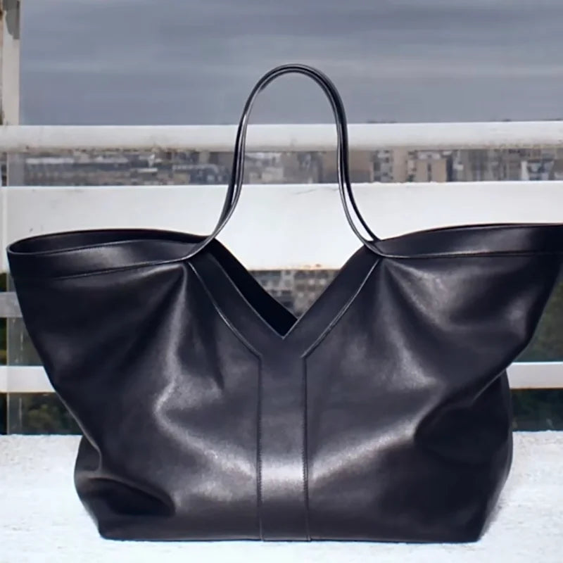 Large black V-cut leather tote bag with double shoulder straps on display