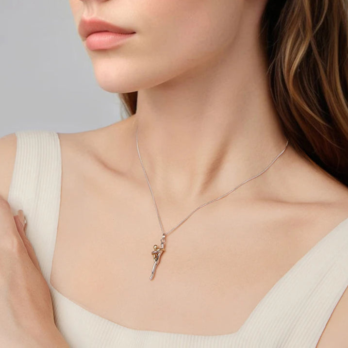 Woman wearing a delicate necklace with a small pendant on a plain background