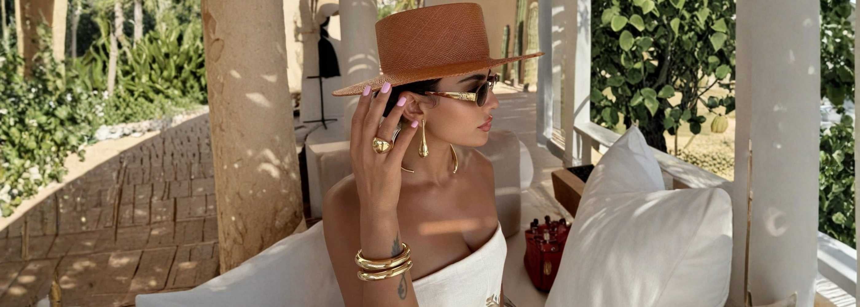Model wearing Murps gold PVD earrings and bracelets outdoors.