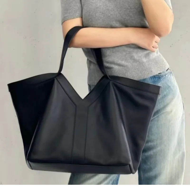 Large black V-cut leather tote bag with double shoulder straps on display